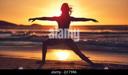 Soyez en paix, pas en morceaux. Silhouette de jeune femme pratiquant le yoga sur la plage. Banque D'Images