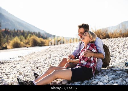 L'Autriche, les Alpes, l'heureux couple en randonnée ayant une pause à un ruisseau Banque D'Images