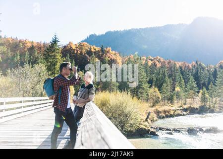 L'Autriche, les Alpes, en couple en randonnée avec man looking through binoculars Banque D'Images