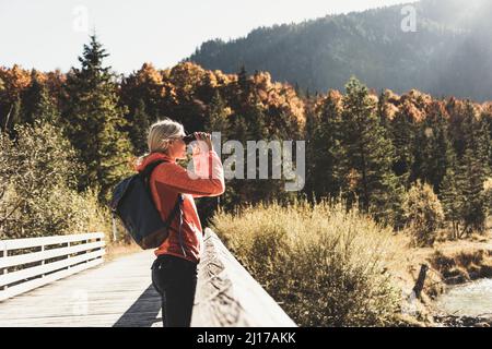 L'Autriche, Alpes, femme en randonnée binoculars Banque D'Images