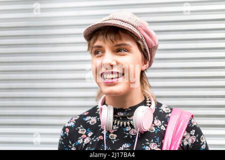 Jeune femme heureuse avec capuchon plat debout devant l'obturateur fermé Banque D'Images