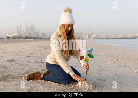 Bonne femme assise sur le sable avec un jouet à volant multicolore à la plage Banque D'Images