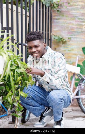 Jeune homme souriant en position de squat à vélo Banque D'Images