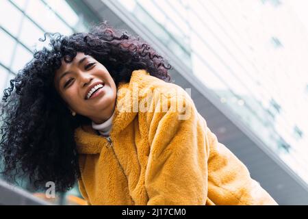 Jeune femme riant avec des cheveux bouclés Banque D'Images