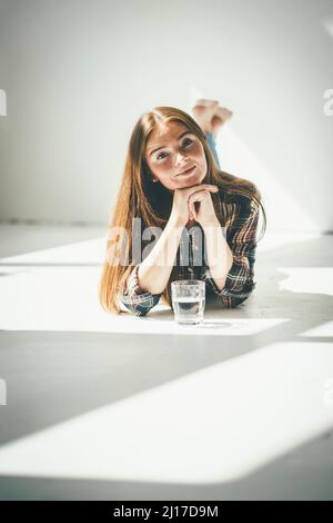 Jeune femme avec la main sur le menton couché à la maison Banque D'Images