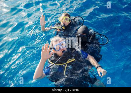 Équipe de plongeurs homme et femme avec équipement de plongée se préparent à plonger sous l'eau dans la mer rouge, vue de dessus. Banque D'Images