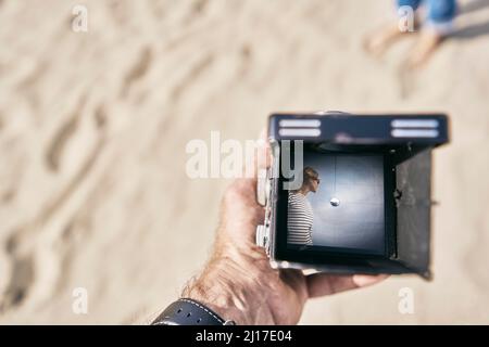 Homme tenant un appareil photo d'époque avec une photo de femme à la plage Banque D'Images