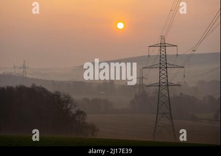 Ledgerwood aux frontières écossaises, Royaume-Uni. 23rd mars 2022. Engery, électricité, électricité. Le soleil se lève un autre jour de prix élevés de l'énergie alors que le coût de la vie continue d'augmenter. La transition vers l'énergie verte est une priorité, mais aussi l'équilibre entre la réduction des coûts de l'énergie actuellement élevée en raison de la pandémie de cavid et de la guerre actuelle en Ukraine et des sanctions contre la Russie. La vue est de pylônes d'électricité et une distance éolienne que le soleil se lève près de Ledgerwood dans les frontières écossaises. Crédit : phil wilkinson/Alay Live News Banque D'Images