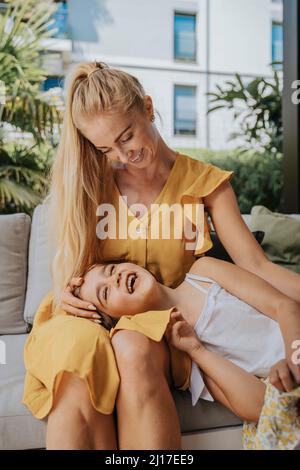 Fille couchée sur les genoux de la mère dans le patio Banque D'Images