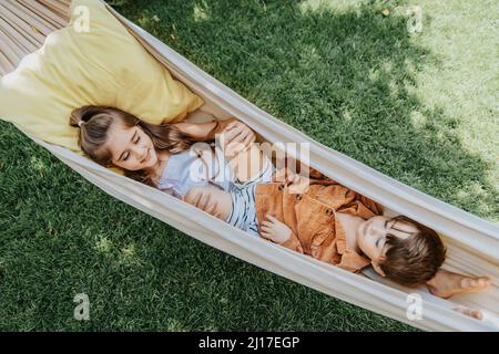 Frères et sœurs se trouvant dans un hamac dans la cour arrière Banque D'Images