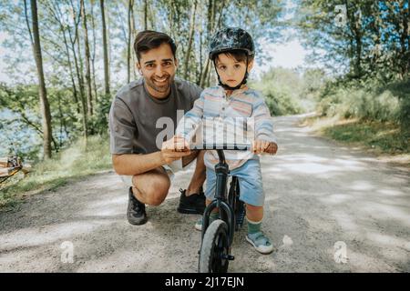Père et fils souriants avec vélo sur la route Banque D'Images