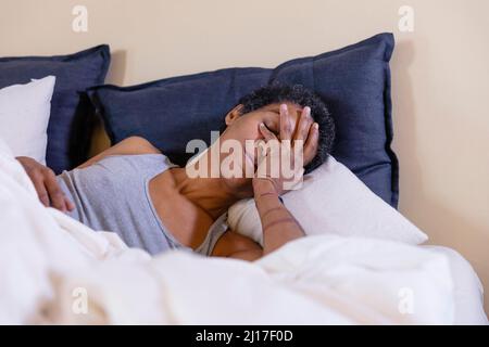 Femme couvrant le visage et allongé sur le lit à la maison Banque D'Images