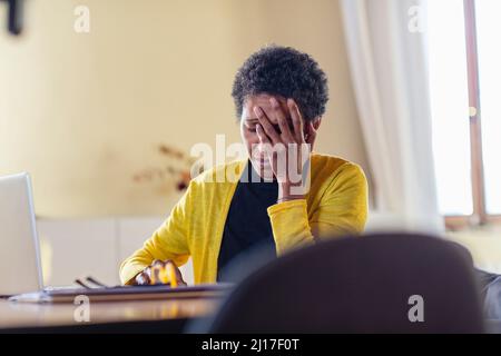 Travailleur indépendant inquiet avec un ordinateur portable au bureau à domicile Banque D'Images