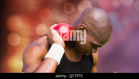 Homme afro-américain pratiquant le tir mis contre des taches de lumière sur fond rouge Banque D'Images