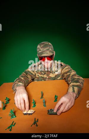 Jeune soldat militaire avec figurines et chars de l'armée sur la table Banque D'Images