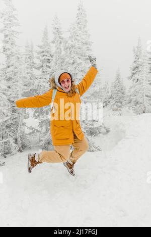 Femme gaie qui bondisse sur la neige en forêt Banque D'Images