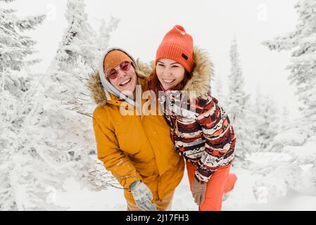 Des amis heureux debout dans la forêt d'hiver en vacances Banque D'Images