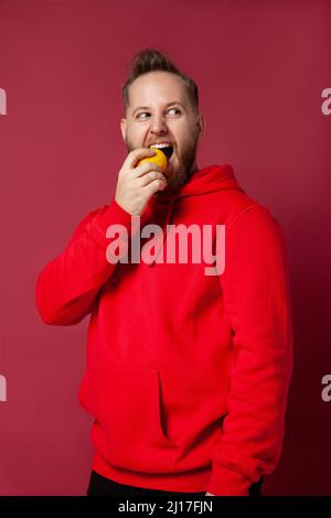 Jeune homme mangeant du citron en studio Banque D'Images