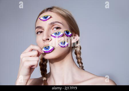 Femme avec des autocollants pour les yeux sur le visage sur fond gris Banque D'Images