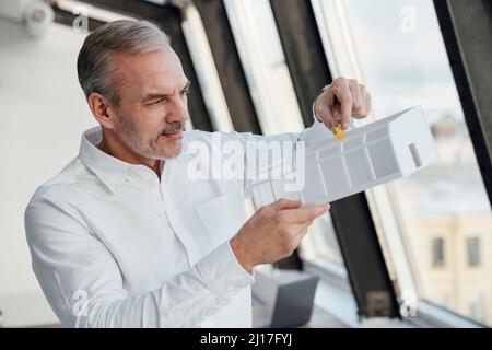 Homme d'affaires examinant le modèle architectural sur le lieu de travail Banque D'Images