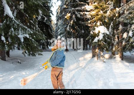 Femme souriante tournant sac de mandarines à la forêt d'hiver Banque D'Images