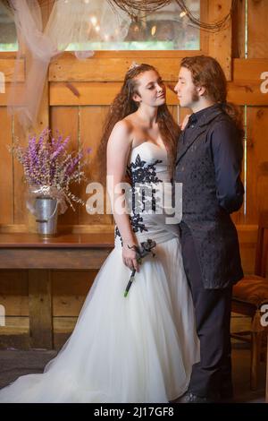 Un jeune couple pose pour une simulation de mariage dans une grange à cheval. Banque D'Images