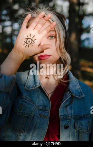 Jeune femme montrant un signe de tatouage oculaire sur sa main Banque D'Images