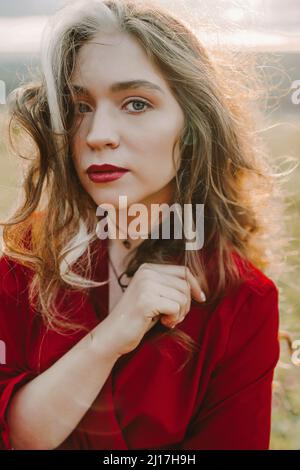 Belle femme en robe rouge debout sur le terrain Banque D'Images