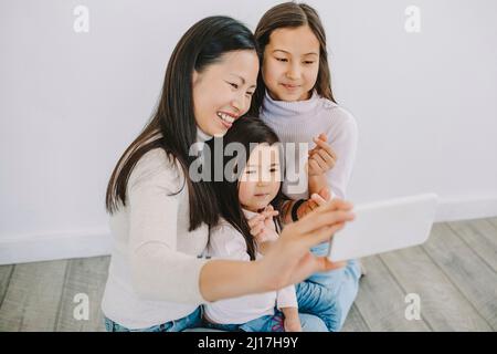 Bonne mère prenant le selfie avec des filles montrant le signe du coeur à la maison Banque D'Images