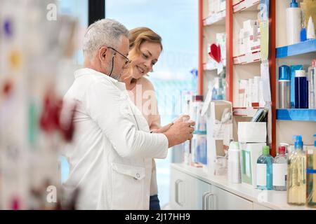 Pharmacien aidant le client à prendre des médicaments dans un magasin de pharmacie Banque D'Images