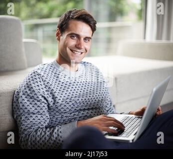Positif sur la technologie. Portrait d'un beau jeune homme utilisant son ordinateur portable. Banque D'Images