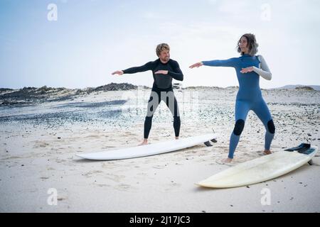Homme enseignant femme cours de surf sur la plage Banque D'Images