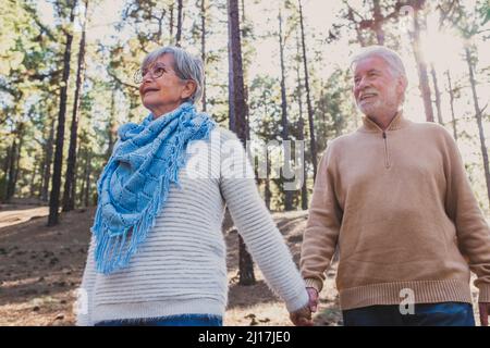 Couple senior souriant tenant la main dans la forêt Banque D'Images