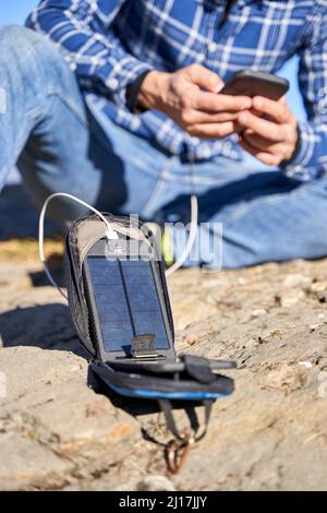 Homme en charge de téléphone portable par panneau solaire portable le jour ensoleillé Banque D'Images