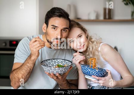 Homme souriant et femme mangeant des spaghetti à la maison Banque D'Images