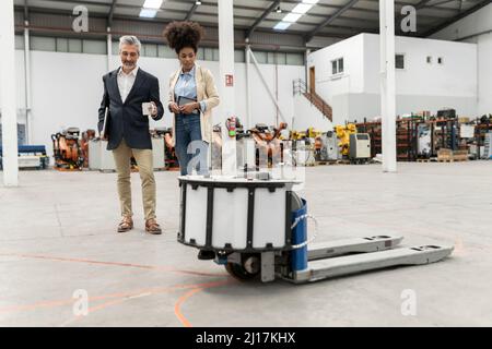 Homme d'affaires et femme d'affaires regardant le transpalette discutant en usine Banque D'Images