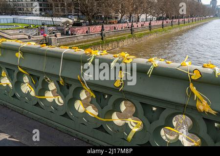 LONDRES, ROYAUME-UNI. 23 mars 2022 .des rubans jaunes sont attachés par des bénévoles de Covid Families UK place sur le pont de Westminster pour marquer le deuxième anniversaire du premier confinement national imposé par le gouvernement. Un silence d'une minute a été observé à midi pour commémorer les victimes de la pandémie du coronavirus. Credit: amer ghazzal / Alamy Live News Banque D'Images