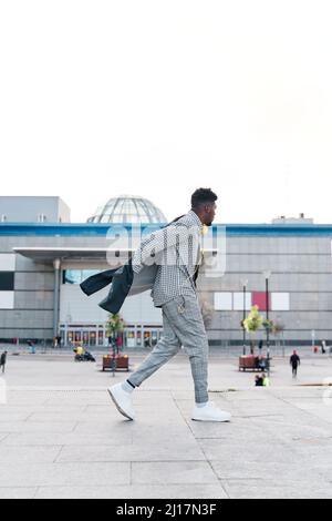 homme marchant dans la ville en mettant sa veste Banque D'Images