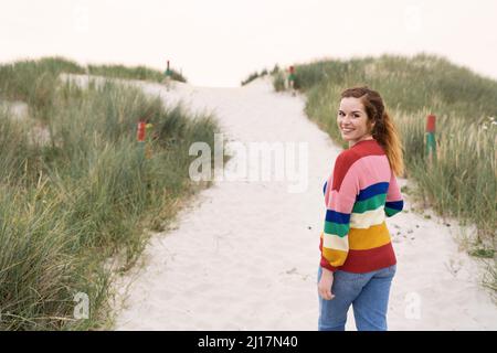 Souriante belle jeune femme marchant sur le sable Banque D'Images
