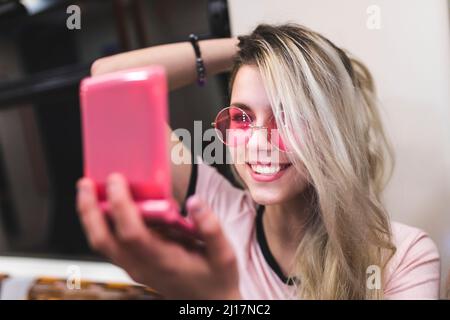 Joyeux adolescent blond avec la main dans les cheveux regardant le miroir Banque D'Images