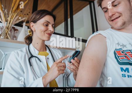 Médecin souriant effectuant un test de glycémie du patient en clinique Banque D'Images