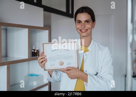 Médecin souriant montrant un certificat en clinique Banque D'Images