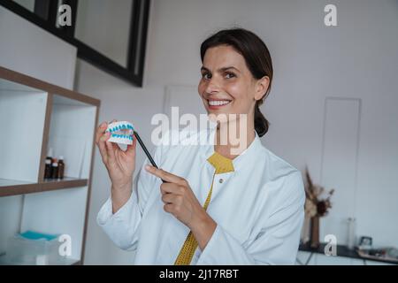 Médecin souriant tenant le modèle de prothèse en clinique Banque D'Images