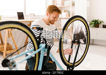 Jeune homme souriant répare le vélo à la maison Banque D'Images