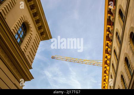 Allemagne, Bavière, Munich, vue à angle bas d'une grue industrielle au-dessus de corniches de stuc Banque D'Images