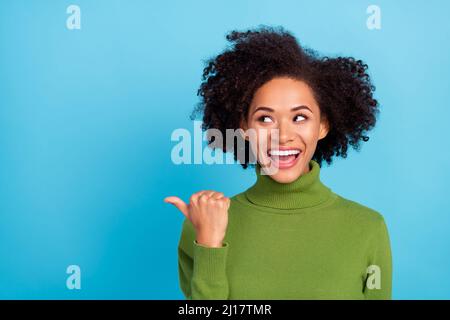 Portrait de la fille drôle excitée regarder directement pouce vide proposition d'espace isolé sur fond bleu de couleur Banque D'Images