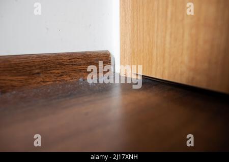 Gros plan des amas de poussière de la maison et araignée sur toile d'araignée dans le coin des lapins de poussière sur le plancher brun négligé coin rempli de la couche de poussière et toile d'araignée Banque D'Images