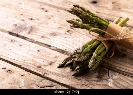 Vue en grand angle des légumes asperges crus attachés avec des cordes sur une table brune en bois Banque D'Images