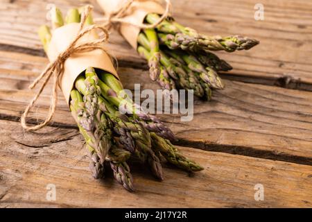 Vue en grand angle des pains d'asperges crus attachés avec des cordes sur une table en bois Banque D'Images