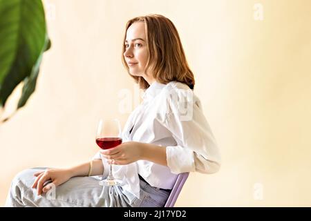 Portrait d'une jeune femme avec un verre de vin rouge entre ses mains. Ressort. Humeur. Banque D'Images